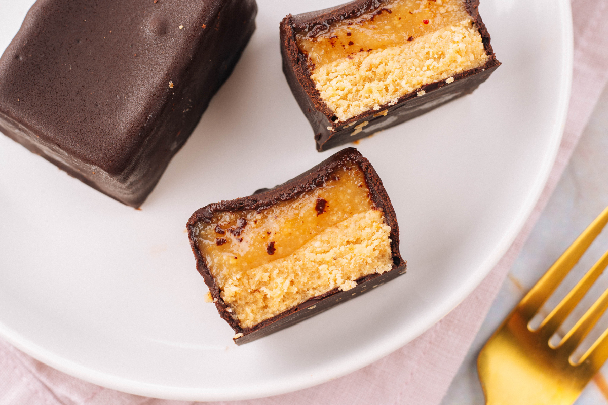Chocolate-covered treats with a creamy center on a white plate with a gold fork.