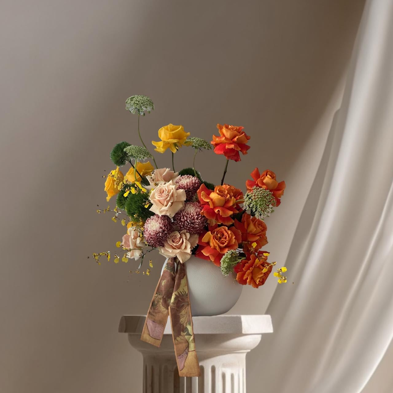 Bouquet of flowers with a colorful ribbon in a white vase against a neutral background