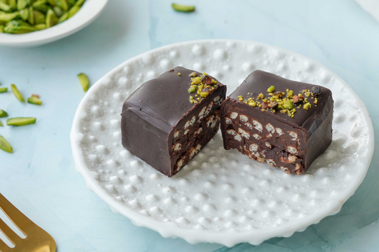 Chocolate dessert with pistachios on a white plate with a light blue background