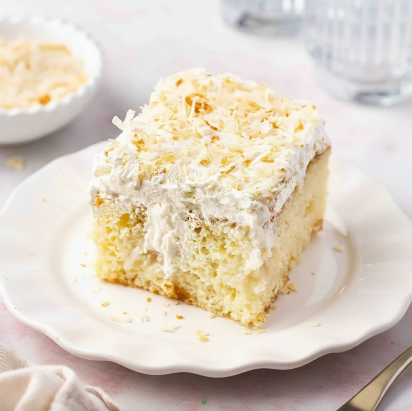 Slice of coconut cake on a white plate with a blurred background