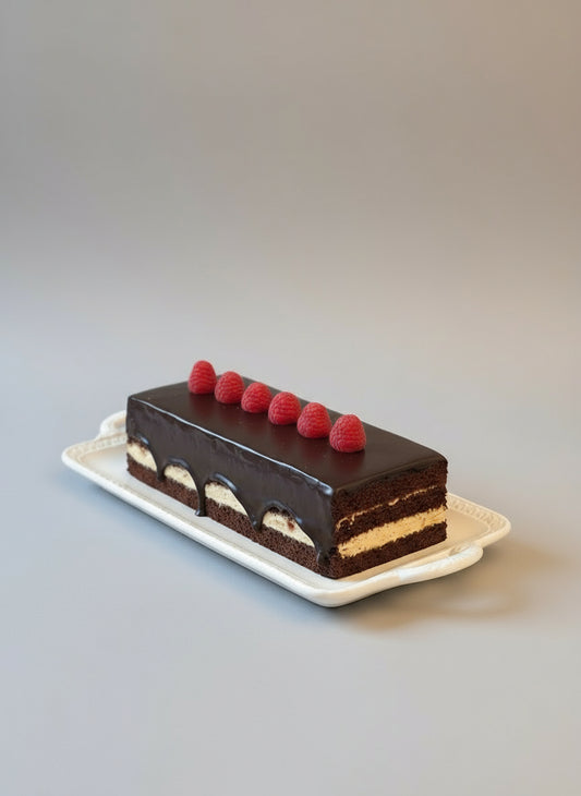Chocolate cake with raspberries on a table with a vase of flowers in the background