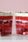Two layered red and white dessert cups with a blurred background