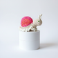 Crocheted snail toy with a pink shell on a light gray background