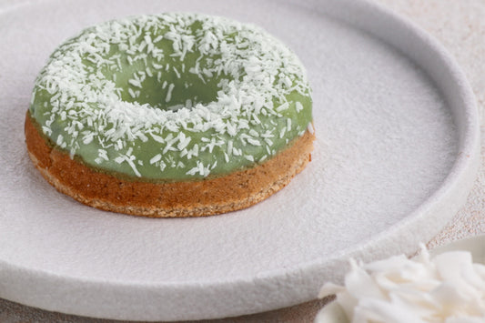 Green doughnut with coconut flakes on a white plate