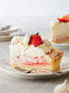Slice of strawberry pie with whipped cream and a strawberry on a plate.