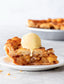 Slice of apple pie with a scoop of vanilla ice cream on a white plate.