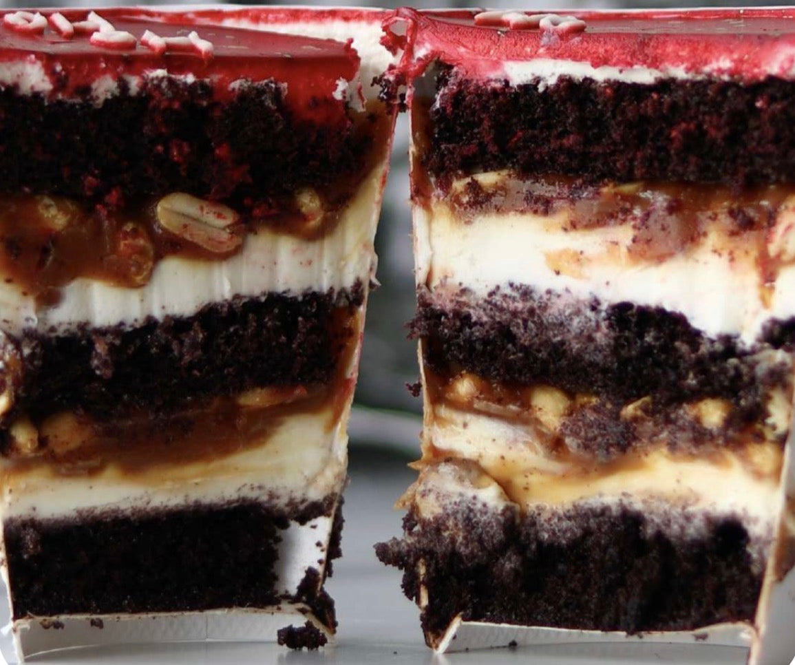 Close-up of a layered dessert with chocolate, cream, and nuts on a white plate.