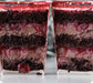 Two slices of layered chocolate cake with cherry filling on a white marble surface.