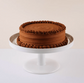 Chocolate cake on a white cake stand with a plain background