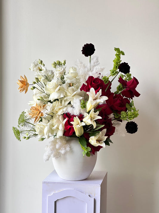 Floral arrangement in a white vase on a white surface with a light gray background