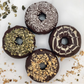 Four chocolate donuts with various toppings on a white surface