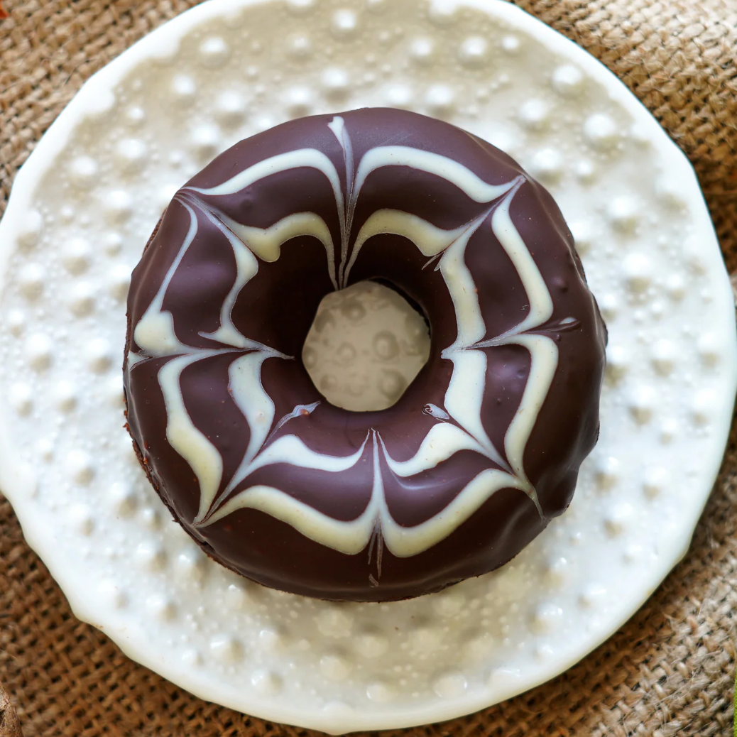 Chocolate donut with white swirl pattern on a textured plate