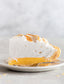 Slice of lemon meringue pie on a plate with a gray background